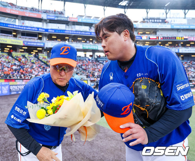 [OSEN=대전, 민경훈 기자] 19일 대전 한화생명 볼파크에서 2026 신한 SOL KBO리그 한화 이글스와 키움 히어로즈의 경기가 열렸다.이날 한화는 류현진, 키움은 박준현이 선발로 나섰다.2회초를 마치고 한화 선발 류현진이 덕아웃 앞에서 한화 김경문 감독에게 한미통산 2,500 탈삼진을 달성 축하 꽃다발을 받고 있다. 2026.07.19 / rumi@osen.co.kr