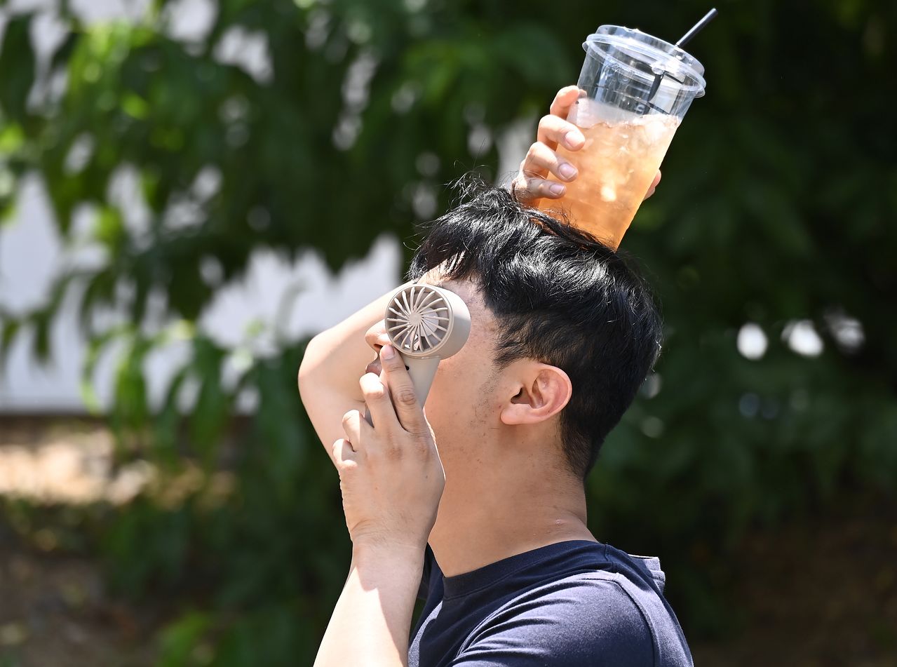 열 스트레스와 탈수가 겹치면 신체 노화가 더 빨라진다. 한 시민이 손선풍기와 얼음이 든 음료컵을 머리에 올리며 더위를 식히고 있다. 사진 뉴시스