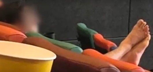 한 영화관에서 부부로 보이는 남녀가 앞좌석 머리받침대에 맨발을 올린 채 영화를 관람하는 모습. 사진 온라인 커뮤니티 '보배드림' 캡처