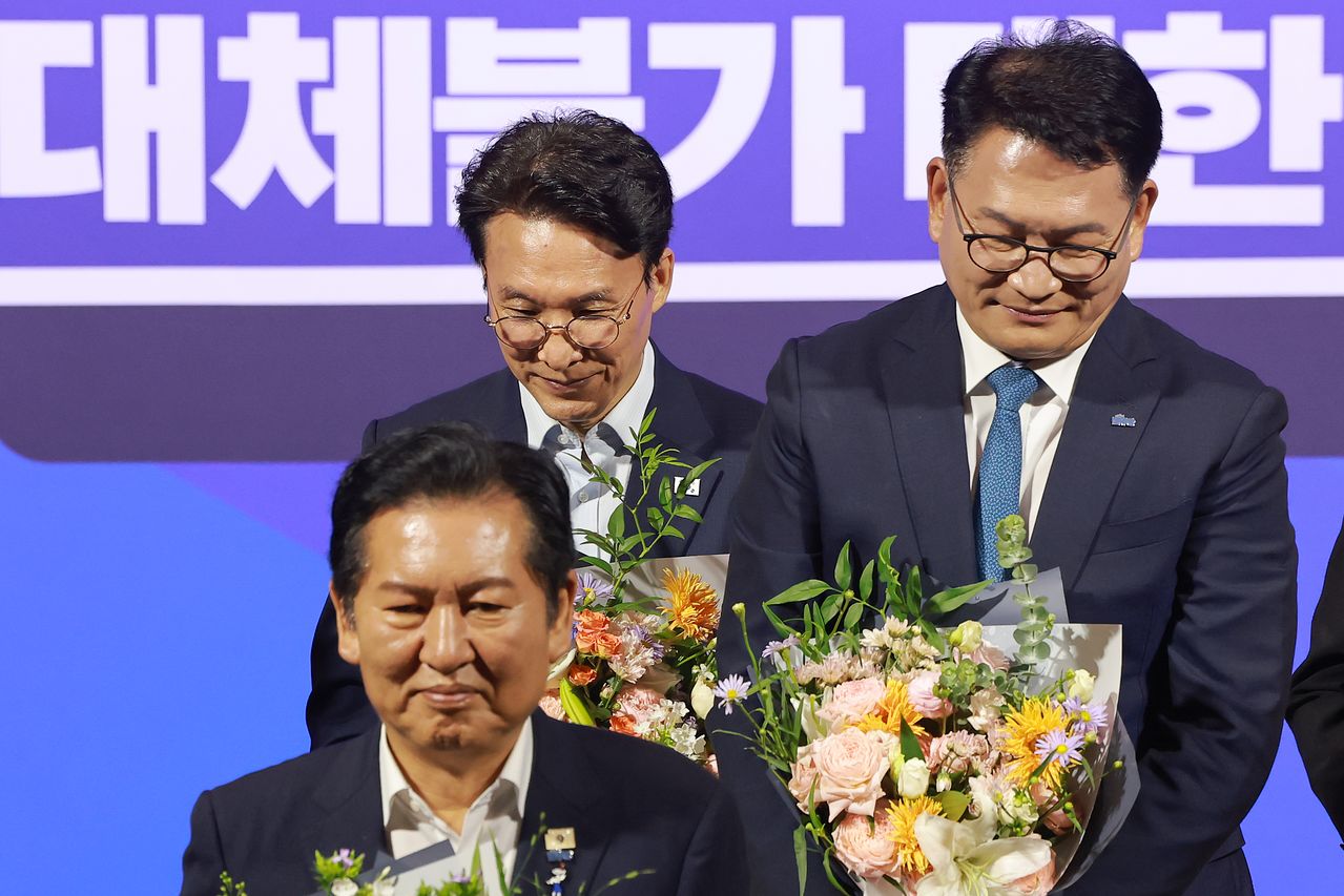 더불어민주당 당 대표 예비경선을 통과한 김민석·정청래·송영길 후보가 23일 국회 의원회관에서 기념 촬영을 마치고 단상에서 내려오고 있다. 연합뉴스 