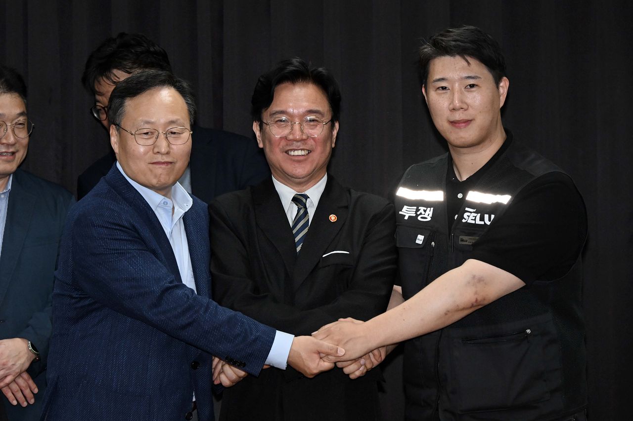 지난 5월 김영훈 고용노동부 장관(가운데)이 경기고용노동청에서 삼성전자 임금협상을 중재한 뒤, 여명구 삼성전자 디바이스솔루션(DS) 피플팀장(맨 왼쪽)과 최승호 삼성그룹 초기업노동조합 삼성전자지부 위원장의 손을 맞잡고 있다. 사진공동취재단