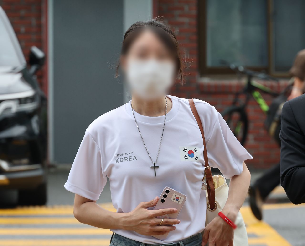 6·3 지방선거 개표소로 사용된 올림픽공원 핸드볼경기장 문 앞에서 체육단체 직원들의 장내 사무실 진입을 막아 업무 방해 혐의를 받는 30대 여성이 지난 10일 서울 송파경찰서에서 조사받기 위해 출석하고 있다.   연합뉴스