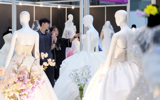 지난해 7월 6일 서울 강남구 삼성동 코엑스에서 열린 2025 추계 웨덱스 웨딩 박람회에서 예비 부부들이 전시된 드레스를 살펴보고 있다. 뉴스1