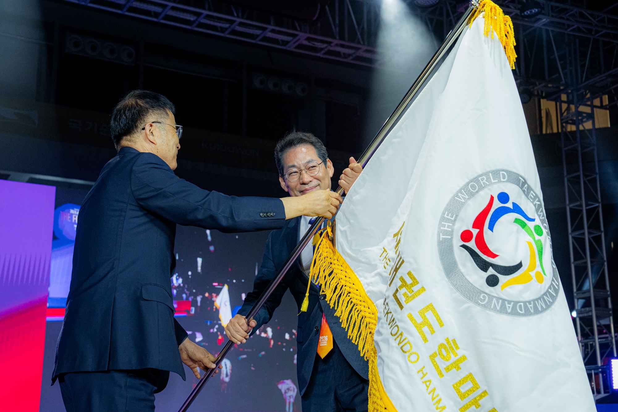 지난 5일 서울 강남구 국기원에서 2026 세계태권도한마당 폐막식이 열렸다. 내년 개최지 순천의 손훈모 시장(오른쪽)에게 한마당기를 전달하는 윤웅석 국기원장. 사진 국기원