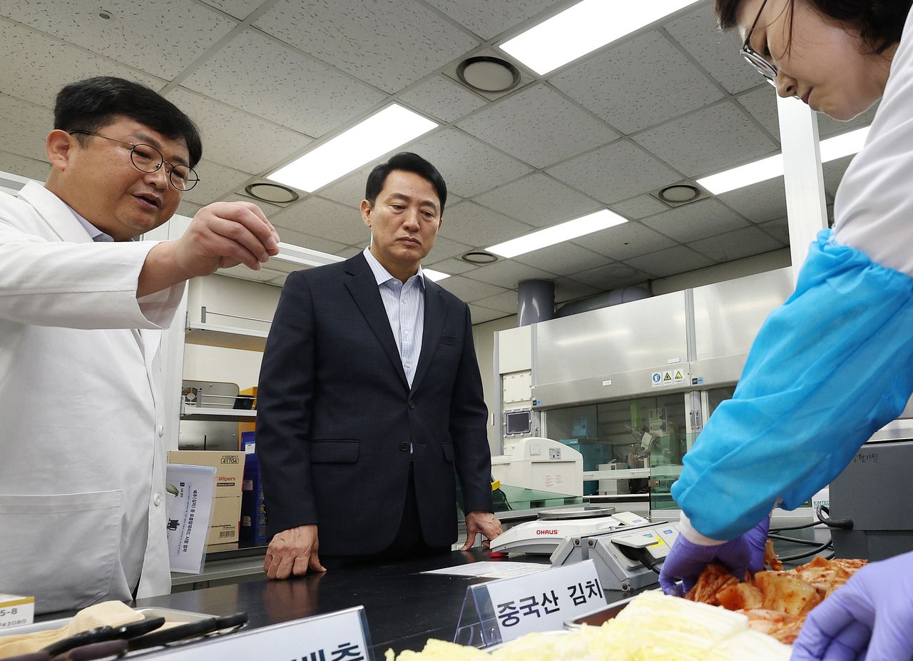 오세훈 서울시장이 31일 서울 서초구 보건환경연구원에서 박주성 보건환경연구원장에게 중국산 김치 관련 안전성 검사 현황에 대해 보고를 받고 있다. 연합뉴스