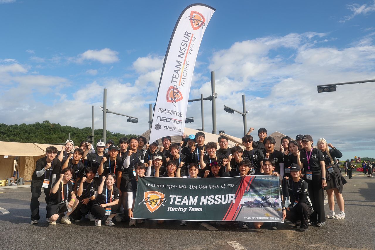 대회 일정을 마친 한국공학대학교 TEAM NSSUR 단원들이 단체 깃발과 현수막을 들고 기념사진을 찍고 있다.