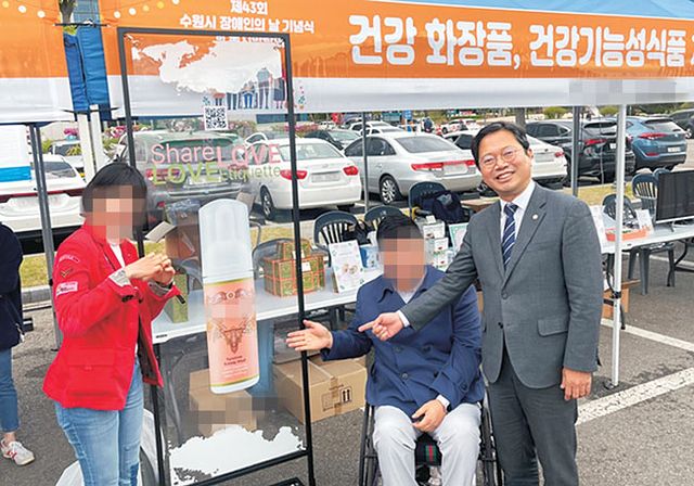 김승원 법무부 장관 후보자(오른쪽)와 청탁 브로커로 의심받고 있는 양모씨(왼쪽)가 2023년 4월 경기도 수원시 장애인의날 기념행사에서 양씨가 대표이사를 맡은 회사의 제품 홍보 사진을 함께 찍은 모습. [사진 양씨 회사 보도자료]
