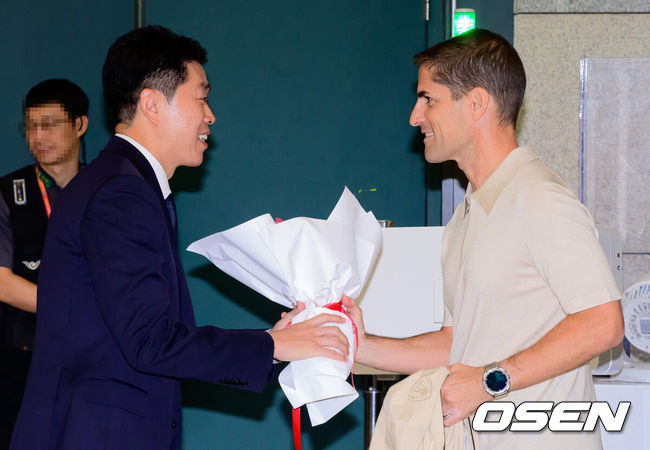 [OSEN=지형준 기자] 로베르토 모레노 신임 대한민국 축구대표팀 임시 감독이 13일 인천국제공항을 통해 외국인 코칭스태프(에두아르도 도캄포 수석코치, 하신트 마그리냐 코치, 빅토르 브라보 데 소토 코치, 하비에로 초카로 피지컬 코치, 니코 보쉬 골키퍼 코치)와 입국했다.계약 기간은 오는 11월 27일까지다. 9월과 10월 4경기, 11월 2경기 등 단 6차례의 A매치에서 자신을 증명해야 한다. 성적과 경기 내용에 따라 내년 1월 열리는 2027 아시아축구연맹(AFC) 아시안컵까지 계약이 연장될 수 있다.로베르토 모레노 감독이 입국장을 나서며 현영민 위원장에게 꽃다발을 건네 받고 있다. 2026.09.13 / jpnews@osen.co.kr