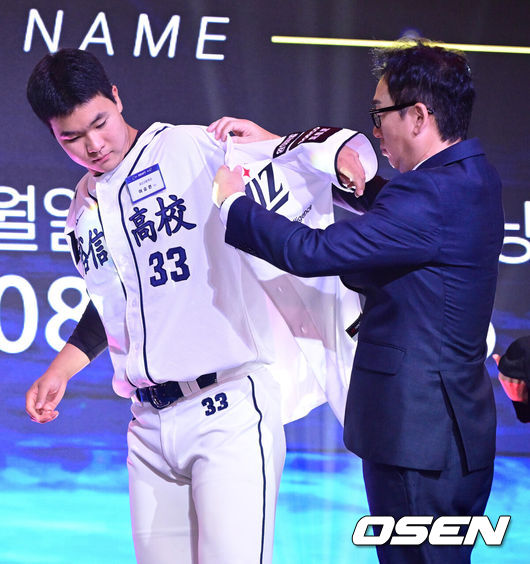 [OSEN=최규한 기자] 21일 오후 서울 잠실동 롯데호텔 월드 크리스탈볼룸에서 ‘2027 KBO 신인드래프트’가 열렸다.이번 신인드래프트는 2025시즌 순위의 역순에 따라 키움 히어로즈, 두산 베어스, KIA 타이거즈, 롯데 자이언츠, KT 위즈, NC 다이노스, 삼성 라이온즈, SSG 랜더스, 한화 이글스, LG 트윈스 순서로 1라운드부터 11라운드까지 지명할 수 있다.유신고 이승원이 KT 1라운드에 지명된 뒤 나도현 단장에게 유니폼을 전달받고 있다. 2026.09.21 / dreamer@osen.co.kr