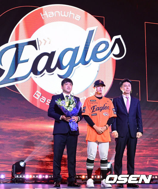 [OSEN=최규한 기자] 21일 오후 서울 잠실동 롯데호텔 월드 크리스탈볼룸에서 ‘2027 KBO 신인드래프트’가 열렸다.이번 신인드래프트는 2025시즌 순위의 역순에 따라 키움 히어로즈, 두산 베어스, KIA 타이거즈, 롯데 자이언츠, KT 위즈, NC 다이노스, 삼성 라이온즈, SSG 랜더스, 한화 이글스, LG 트윈스 순서로 1라운드부터 11라운드까지 지명할 수 있다.설악고 민주홍이 한화 1라운드에 지명된 뒤 손혁 단장과 기념촬영을 하고 있다. 2026.09.21 / dreamer@osen.co.kr