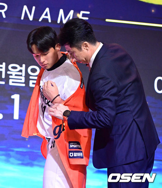 [OSEN=최규한 기자] 21일 오후 서울 잠실동 롯데호텔 월드 크리스탈볼룸에서 ‘2027 KBO 신인드래프트’가 열렸다.이번 신인드래프트는 2025시즌 순위의 역순에 따라 키움 히어로즈, 두산 베어스, KIA 타이거즈, 롯데 자이언츠, KT 위즈, NC 다이노스, 삼성 라이온즈, SSG 랜더스, 한화 이글스, LG 트윈스 순서로 1라운드부터 11라운드까지 지명할 수 있다.설악고 민주홍이 한화 1라운드에 지명된 뒤 손혁 단장에게 유니폼을 전달받고 있다. 2026.09.21 / dreamer@osen.co.kr