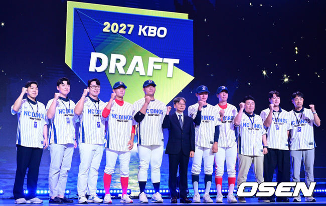 [OSEN=최규한 기자] 21일 오후 서울 잠실동 롯데호텔 월드 크리스탈볼룸에서 ‘2027 KBO 신인드래프트’가 열렸다.이번 신인드래프트는 2025시즌 순위의 역순에 따라 키움 히어로즈, 두산 베어스, KIA 타이거즈, 롯데 자이언츠, KT 위즈, NC 다이노스, 삼성 라이온즈, SSG 랜더스, 한화 이글스, LG 트윈스 순서로 1라운드부터 11라운드까지 지명할 수 있다.NC 1라운드 경남고 박보승을 비롯한 드래프트 지명자들과 임순남 단장을 비롯한 구단 관계들이 기념촬영을 있다. 2026.09.21 / dreamer@osen.co.kr