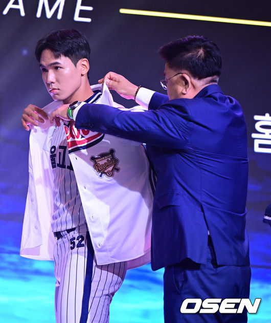 [OSEN=최규한 기자] 21일 오후 서울 잠실동 롯데호텔 월드 크리스탈볼룸에서 ‘2027 KBO 신인드래프트’가 열렸다.이번 신인드래프트는 2025시즌 순위의 역순에 따라 키움 히어로즈, 두산 베어스, KIA 타이거즈, 롯데 자이언츠, KT 위즈, NC 다이노스, 삼성 라이온즈, SSG 랜더스, 한화 이글스, LG 트윈스 순서로 1라운드부터 11라운드까지 지명할 수 있다.서울고 김지우가 전체 2번으로 두산 베어스에 지명된 뒤 유니폼을 입고 있다. 2026.09.21 / dreamer@osen.co.kr
