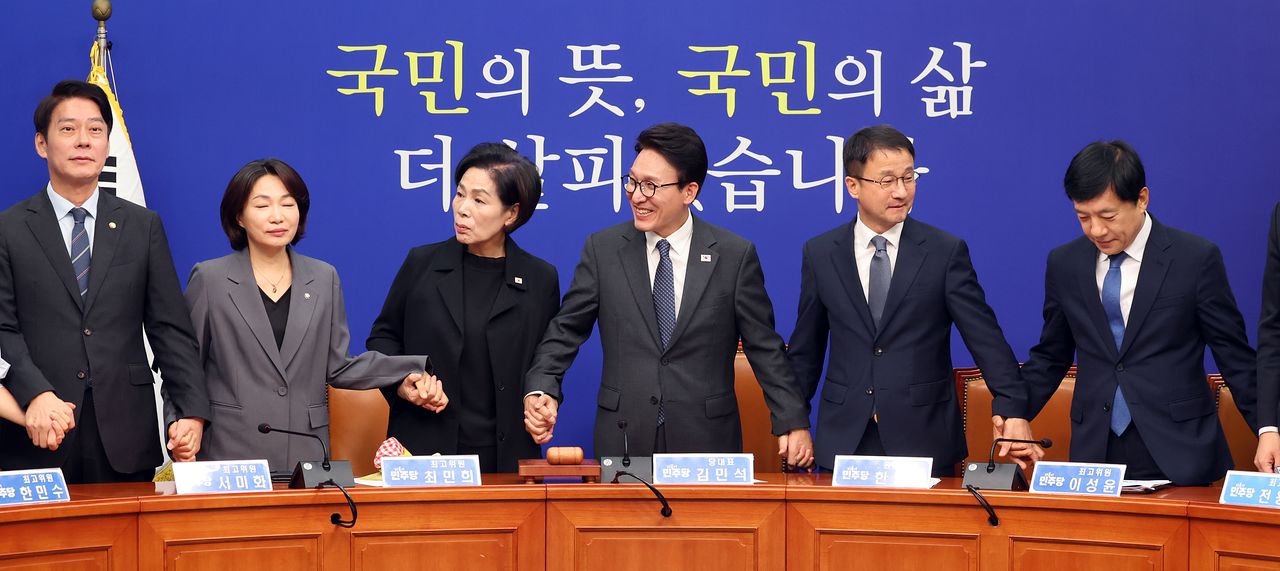 김민석 더불어민주당 대표와 지도부가 23일 오전 서울 여의도 국회에서 열린 최고위원회의에서 인사를 위해 손을 맞잡고 있다. 뉴스1