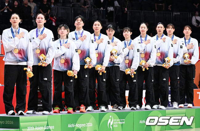 [OSEN=아이치현(일본), 박준형 기자] 남자 대표팀에 이어 여자 대표팀도 결승에서 일본을 꺾고 금메달을 목에 걸었다. 한국 농구가 일본 홈코트에서 '남녀 동반' 우승을 완성했다.박수호 감독이 이끄는 한국 대표팀은 26일 일본 나고야 아이치 인터내셔널 아레나에서 열린 2026년 아이치·나고야 아시안게임 여자농구 결승전에서 일본을 75-70으로 누르고 우승을 차지했다.시상식에서 여자 농구대표팀이 국민의례를 하고 있다.    2026.09.26 / soul1014@osen.co.kr