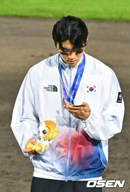 [OSEN=도요하시(일본), 박준형 기자] 한국야구가 우여곡절 끝 아시안게임 5회 연속 금메달을 해냈다. 류지현 감독이 이끄는 한국 야구대표팀은 27일 일본 아이치현 도요하시 시민구장에서 열린 2026 아이치-나고야 아시안게임 일본과 결승전에서 3-1로 승리했다.시상식에서 김도영이 금메달을 바라보고 있다. 2026.09.27 / soul1014@osen.co.kr