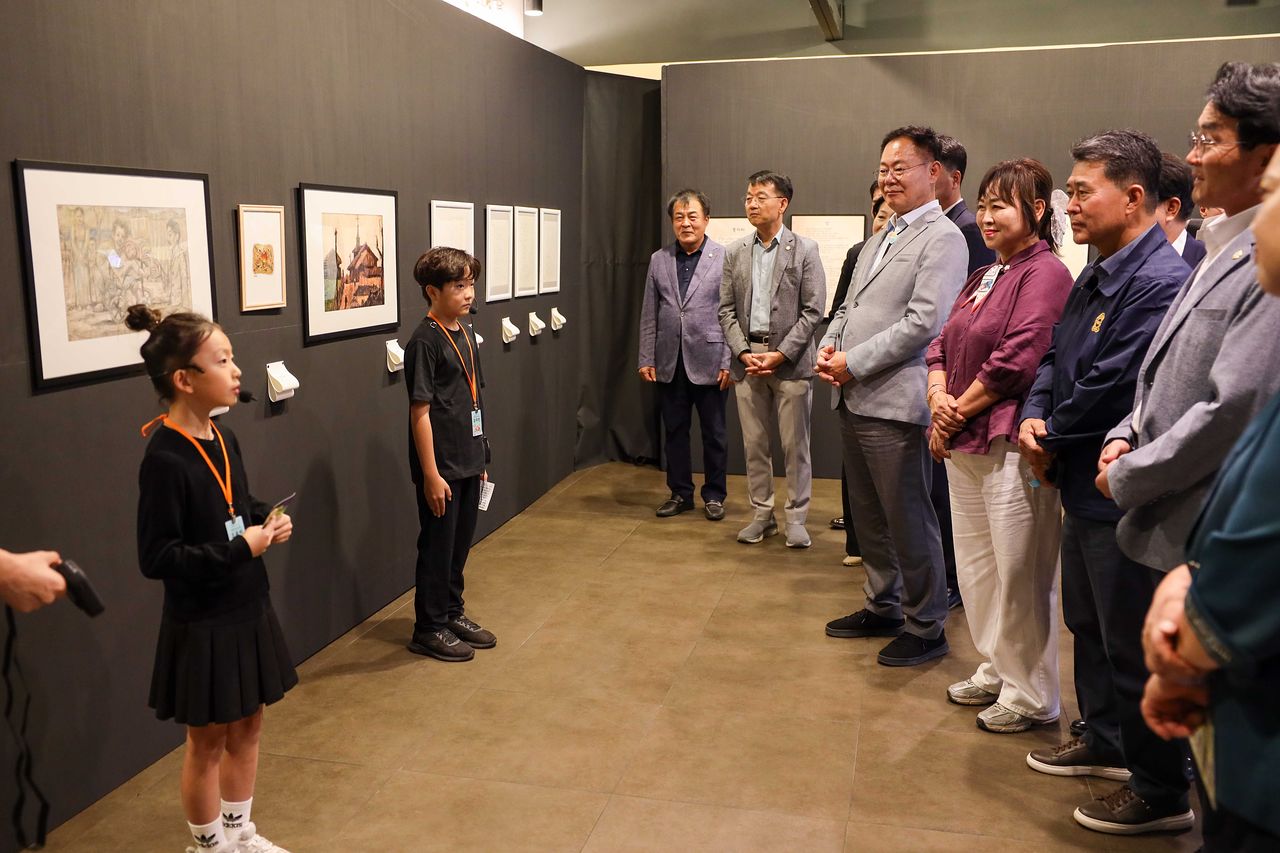 김재욱 칠곡군수와 군의원 등 참석자들이 지난 17일 ‘2026 제4회 칠곡 트랜스미디어 축제’ 전시장에서 어린이 도슨트의 설명을 들으며 작품을 관람하고 있다. 사진 칠곡군