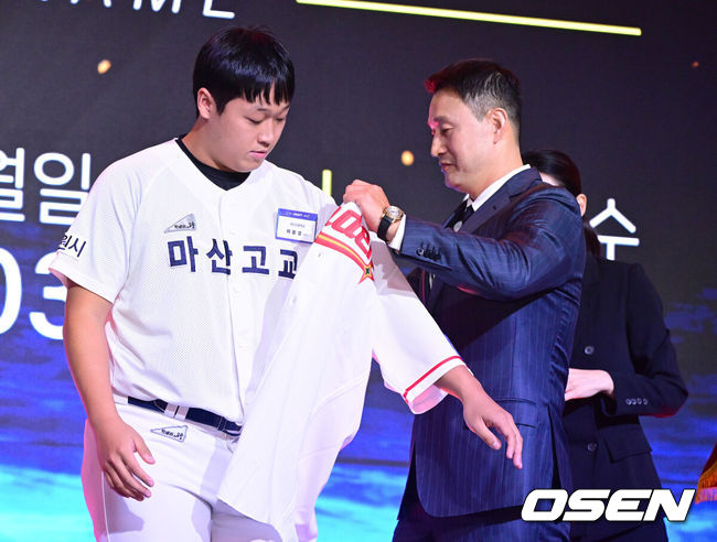 [OSEN=최규한 기자] 21일 오후 서울 잠실동 롯데호텔 월드 크리스탈볼룸에서 ‘2027 KBO 신인드래프트’가 열렸다. 마산고 이윤성이 SSG 1라운드에 지명된 뒤 김재현에게 유니폼을 전달받고 있다. 2026.09.21 / dreamer@osen.co.kr
