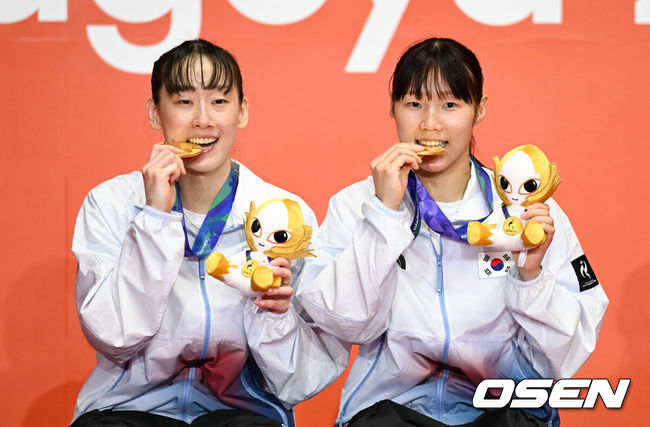 [OSEN=아이치현(일본), 박준형 기자] 마침내 한국 배드민턴의 2026아이치·나고야 아시안게임 첫 금메달이 탄생했다.이소희-백하나(이상 인천국제공항) 조가 명승부 끝에 만리장성을 넘고 여자복식 정상에 올랐다.배드민턴 여자 복식 세계 2위 이소희-백하나 조는 29일일본 이치노미야 시립 체육관에서 열린 대회 여자 복식 결승전에서중국의 류성수-탄닝 조(세계 1위)를 상대로 2-1(26-28 21-18 21-18)로 역전승을 거두며 우승했다.1게임 41분, 2게임 28분, 3게임 37분으로 총 106분이 걸린 혈투였다.이소희-백하나가 금메달을 물고 포즈를 취하고 있다.    2026.09.29 / soul1014@osen.co.kr
