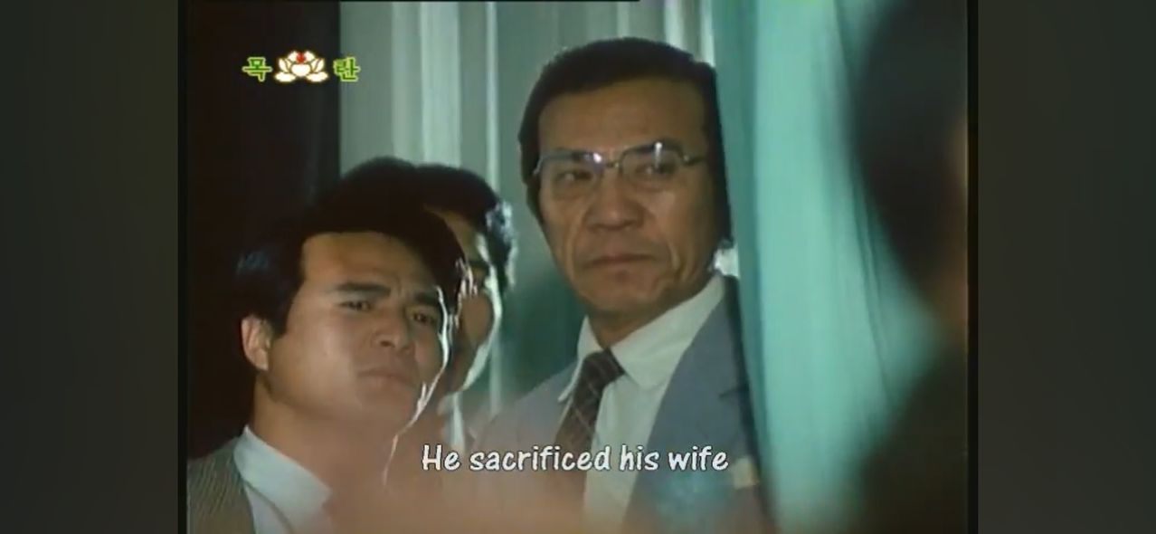 북한 드라마 '민족과 운명' 제1편 말미에 등장하는 1974년 광복절 기념식 장면. 박정희 대통령 경호원(오른쪽)이 무대 뒤에서 육영수 여사를 쏘려고 기다리고 있다. [유튜브 캡처]