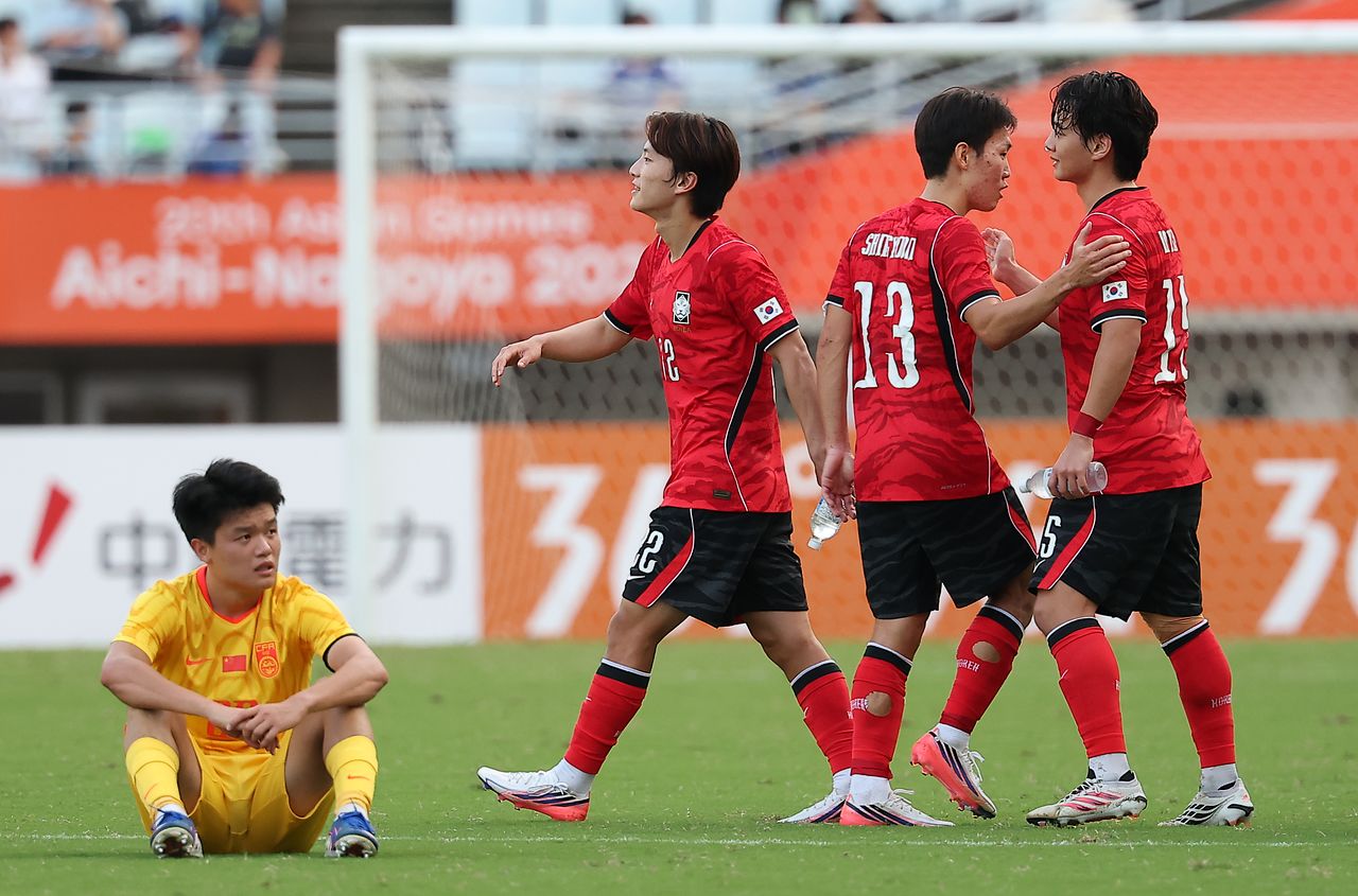 그라운드 주저앉아 허탈한 표정을 짓는 중국 선수(왼쪽) 옆에서 2-1 승리를 자축하는 아시안게임 한국 축구대표팀 선수들. 결승에 진출한 한국은 대회 4연패에 도전한다. [연합뉴스]