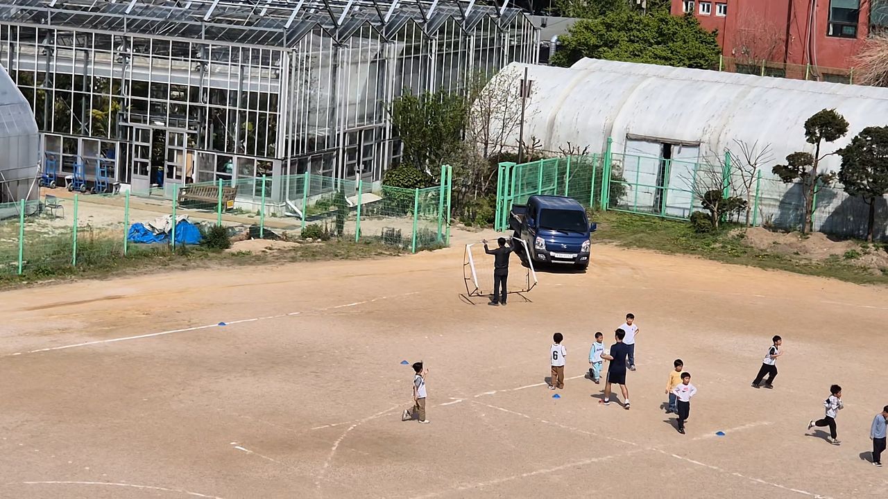 지난 4월 체육 수업 중인 서울 덕수초 운동장에 트럭이 나오고 있는 모습. 화훼 관련 업무를 담당하는 작업자가 골대를 치우고 있다. 뒤쪽엔 운동장에 설치된 실내온실과 비닐하우스. 덕수초비대위