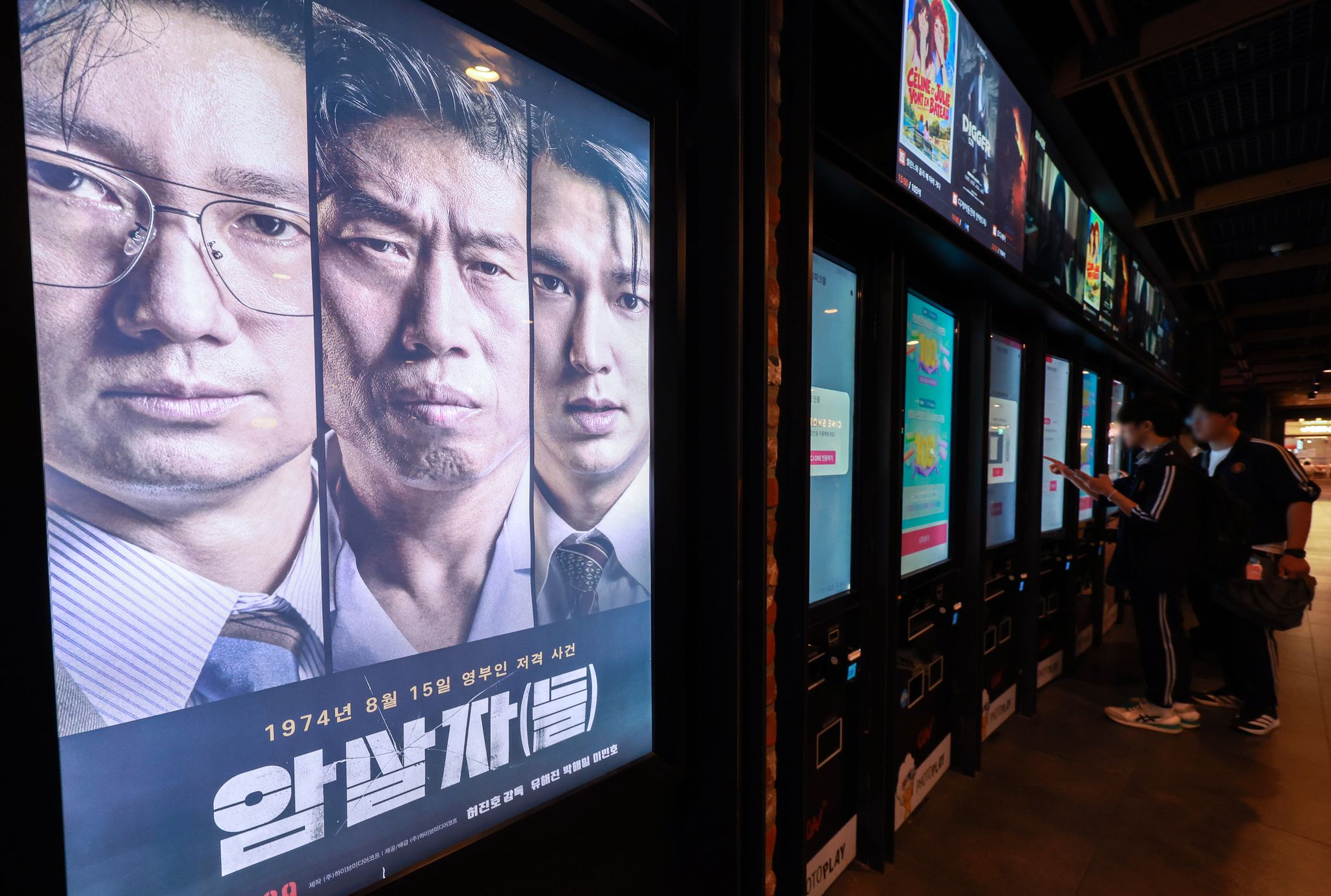 영화 ‘암살자(들)’이 역사 왜곡을 둘러싼 정치권 논란 속에서도 전체 박스오피스 1위를 탈환하며 누적 관객 수 182만 명을 넘어선 2일 서울 시내 한 영화관을 찾은 관람객들이 티켓을 구매하고 있다. 뉴스1