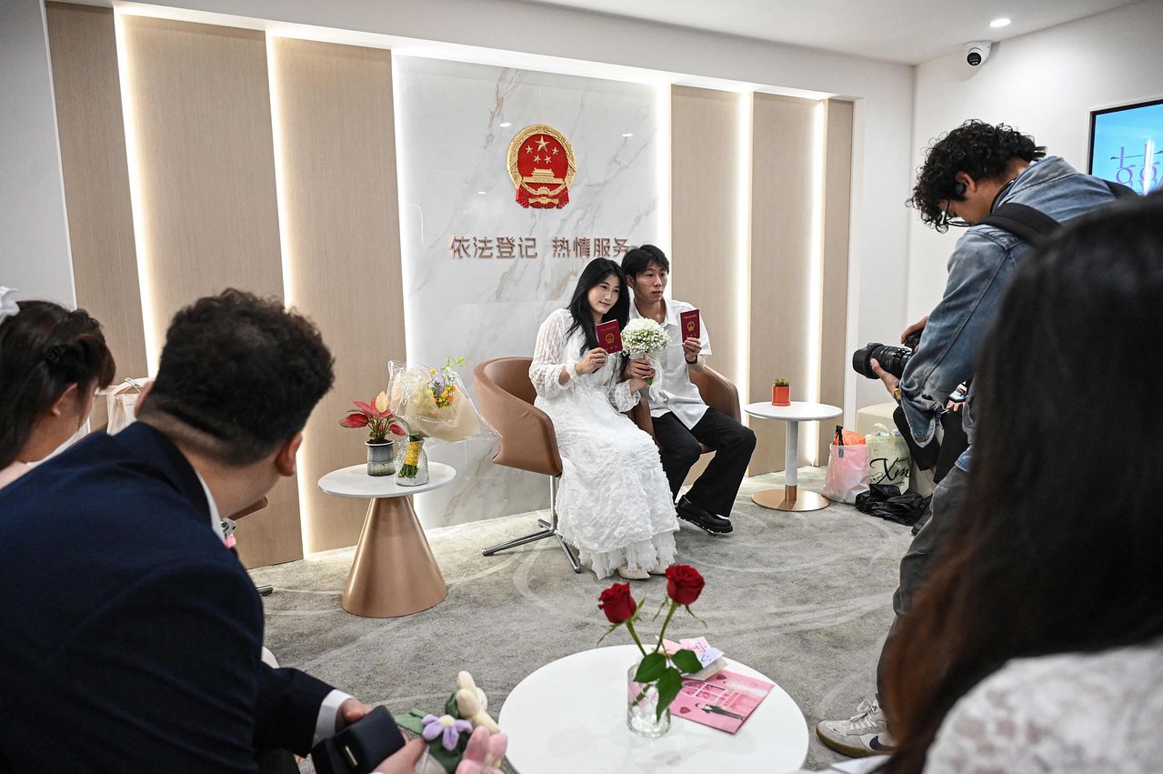 지난 5월 중국 상하이의 한 혼인등기처에서 한 부부가 결혼증을 받은 사진을 찍기 위해 포즈를 취하고 있다. AFP=연합뉴스