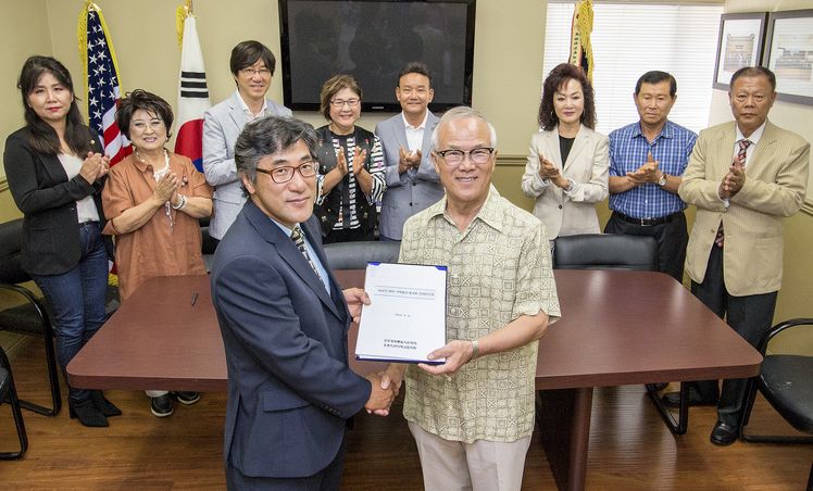 지난 6일 열린 인수인계식에서 자문위원들의 박수 가운데 오득재(앞줄 왼쪽) 신임회장이 김진모 전임회장에게 인수인계 서류를 전해 받고 있다.