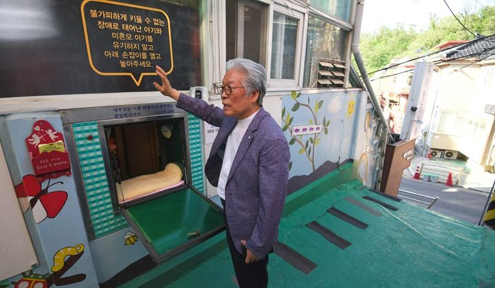 Pastor Lee Jong-Rak standing in front of a baby box that offers a place for unwanted babies to be left and be cared for. [Source: Associated Free Press]
