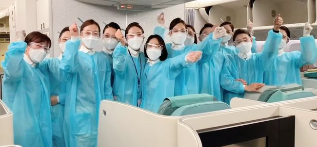방호복과 고글, 마스크, 장갑 등을 착용한 대한항공 승무원들이 기내 서비스에 앞서 화이팅을 외치고 있다. [대한항공 제공]
