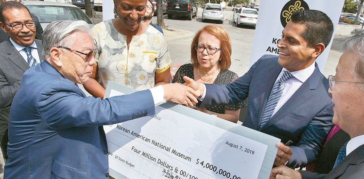 한미박물관 이사회 홍명기 이사장이 가주 정부 지원금을 전달받고 미겔 산티아고 하원의원과 악수하고 있다. 김상진 기자