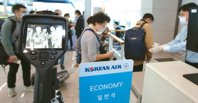 대한항공이 국적기로는 처음으로 마스크 착용 거부 승객의 탑승을 제한한다. 탑승 수속 중 승객의 발열 검사 및 마스크 착용을 확인하고 있는 모습. [대한항공 제공]