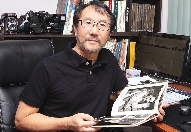 김상동씨가 작업실을 청소하고 김행오씨 사진집을 보고 있다. [김상동씨 제공]