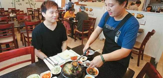 삼계탕 전문 식당들은 보양 성분을 강화한 새로운 메뉴로 경쟁하고 있다. 초복을 하루 앞둔 11일 올림픽 길의 '죽향'에서 한 고객이 주문한 삼계탕을 보고 있다. 김상진 기자