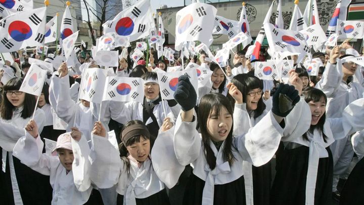 Children dressed in traditional Korean dresses waving the South Korean flag. [Source: Associated Press, Ahn Young-Joon]