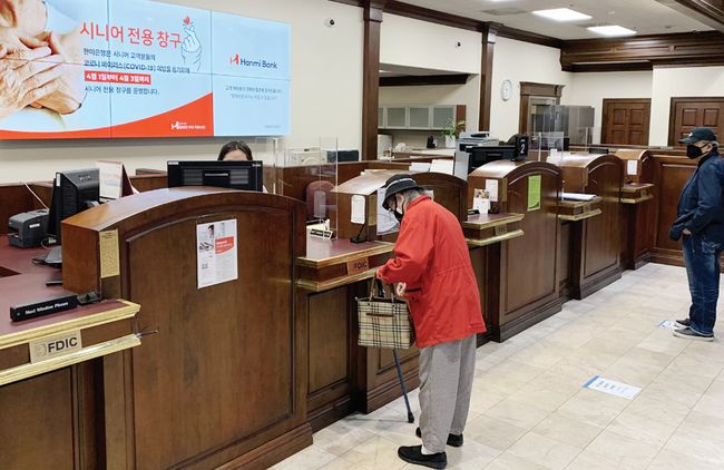 한미은행이 스니즈가드와 시니어 전용 창구 등의 코로나19 예방책을 도입했다. 시니어 고객이 전용 창구에서 은행 업무를 보고 있다. [한미은행제공]