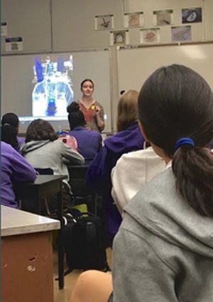Madeline Holtz giving a small demo explaining the chemical reaction behind hydrogen peroxide and yeast, mixed with dish soap.