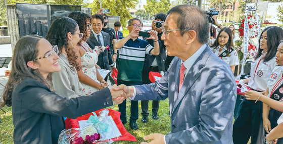 25일 열린 한국전쟁 75주년 행사에서 강석희(오른쪽) 전 어바인 시장이 푸에르토리코 출신 참전용사의 후손들에게 장학금을 전달하고 있다. 김상진 기자