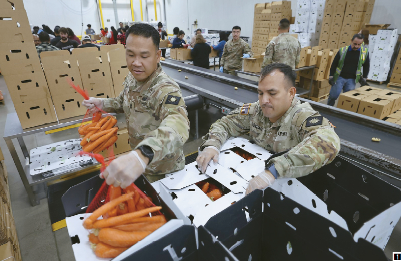 주 방위군 상사 윌존 산토스(가운데)와 병장 루이스 곤살레스가 LA 지역 푸드뱅크에서 농산물 상자를 포장하는 일을 돕고 있다. [앨런 J. 섀번 / LA타임스]