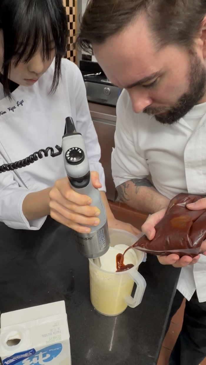[Head Chef Herlander Fernandes and young chef Kyu Lyn Kim preparing a kimchi emulsion together.”(Courtesy of KYCT / Reported by student correspondent, Munsu Kim.”)]
