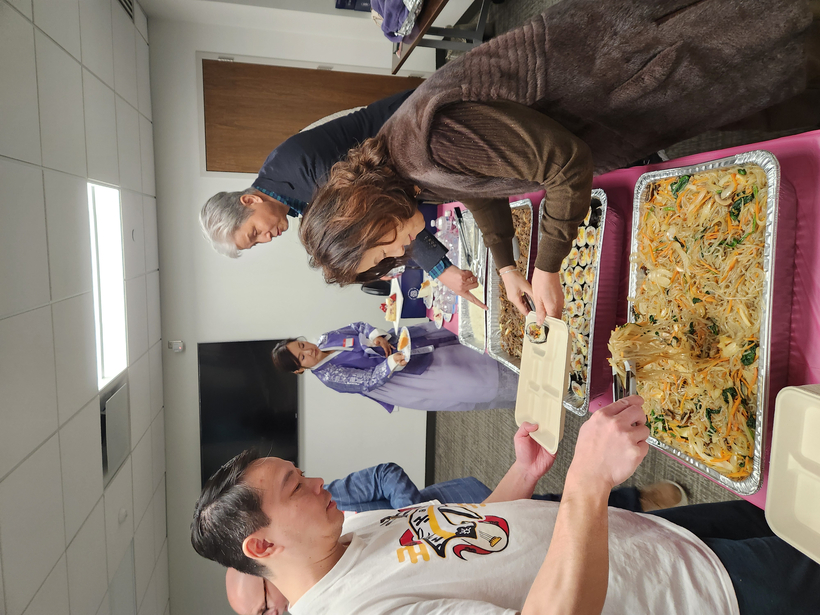 참석자들의 한국의 잡채와 김밥을 접시에 담고 있다.