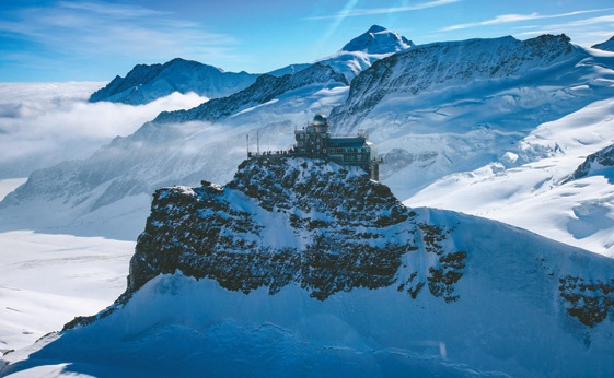 알프스를 대표하는 아이거·묀히·융프라우가 설원 위로 장엄하게 펼쳐지고, 정상의 전망대가 극적인 풍광을 더하고 있다. 