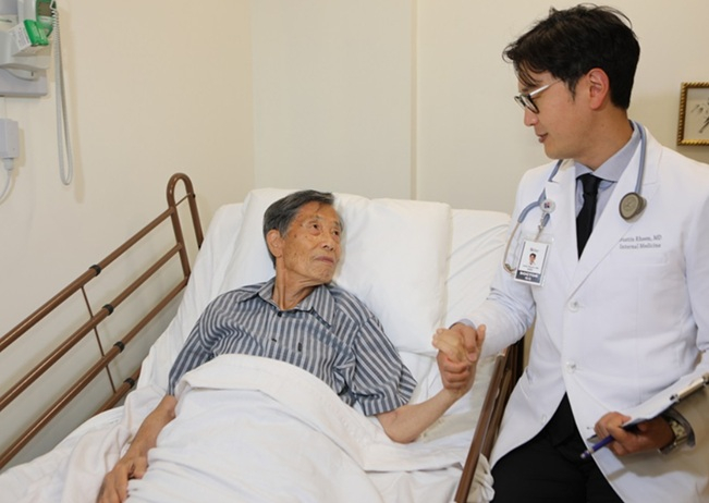임영빈 박사가 병실에서 환자의 손을 잡고 상태를 살피며 대화를 나누고 있다.