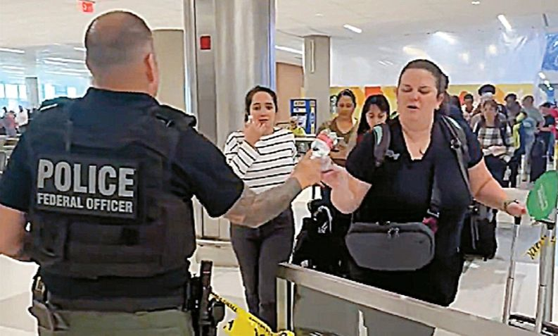 ICE 요원이 한 공항 보안검색대에서 승객에게 생수병을 나눠주고 있다. [CBS 캡쳐]