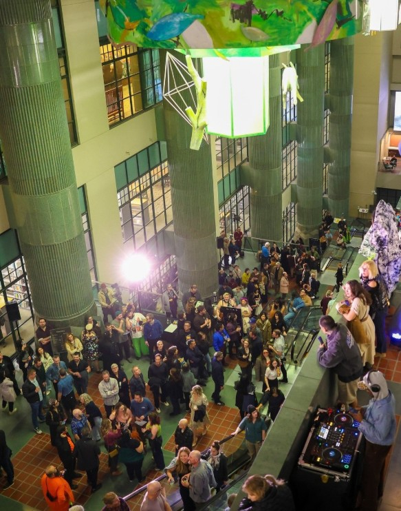 LA다운타운 중앙도서관 내부에서 열린 야간 행사에서 관람객들이 공연과 전시를 즐기고 있다. 높은 천장과 기둥 사이로 설치된 조형물 아래에서 시민들이 어우러진 가운데, 한쪽에서는 DJ가 음악을 틀며 축제 분위기를 더하고 있다.