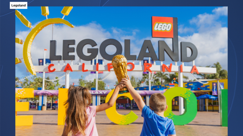 레고랜드 캘리포니아 입구 앞에서 어린이 두 명이 레고로 만든 월드컵 트로피를 함께 들어 올리고 있다.