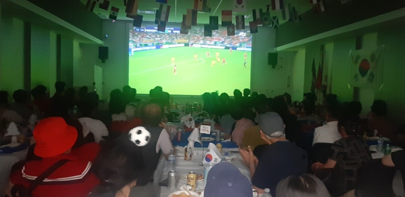 한인신협과 코윈 밴쿠버가 마련한 응원 현장에서 한인들이 대형 스크린을 통해 펼쳐지는 한국 대표팀의 조별리그 3차전 경기를 관람하고 있다. 