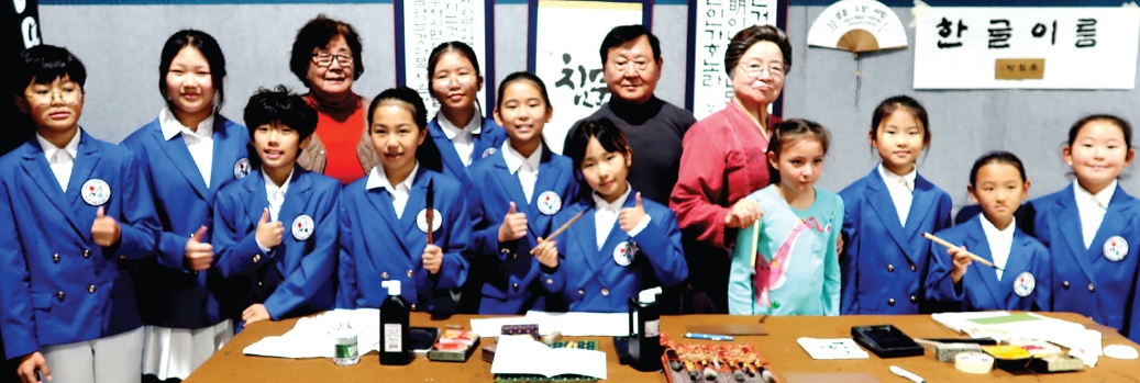 지난 13일 퀸즈 뉴욕우리교회에서 열린 한글날 기념행사에서 미주한인서화협회 현운 박원선 전 회장과 관계자들이 어린이들에게 붓글씨로 한글 이름을 가르쳐주고 있다. 행사에 참가한 학생들은 직접 자신의 이름을 받아보며 한글의 소중함과 예술적 가치를 체험했다.  [미주한인서화협회]