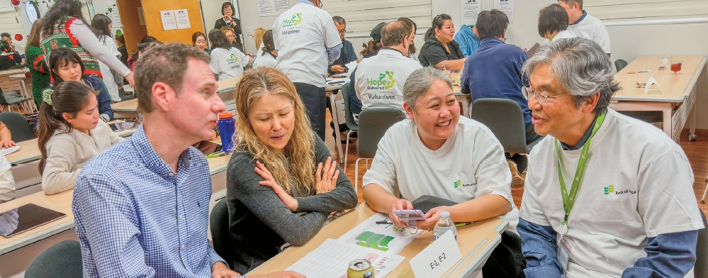 케빈 김(맨 오른쪽) 행장과 자원봉사자들이 16일 열린 ‘호프 딜리버드’ 행사에 참석한 가족에게 연말 쇼핑 주의점에 대해 설명하고 있다. 김상진 기자